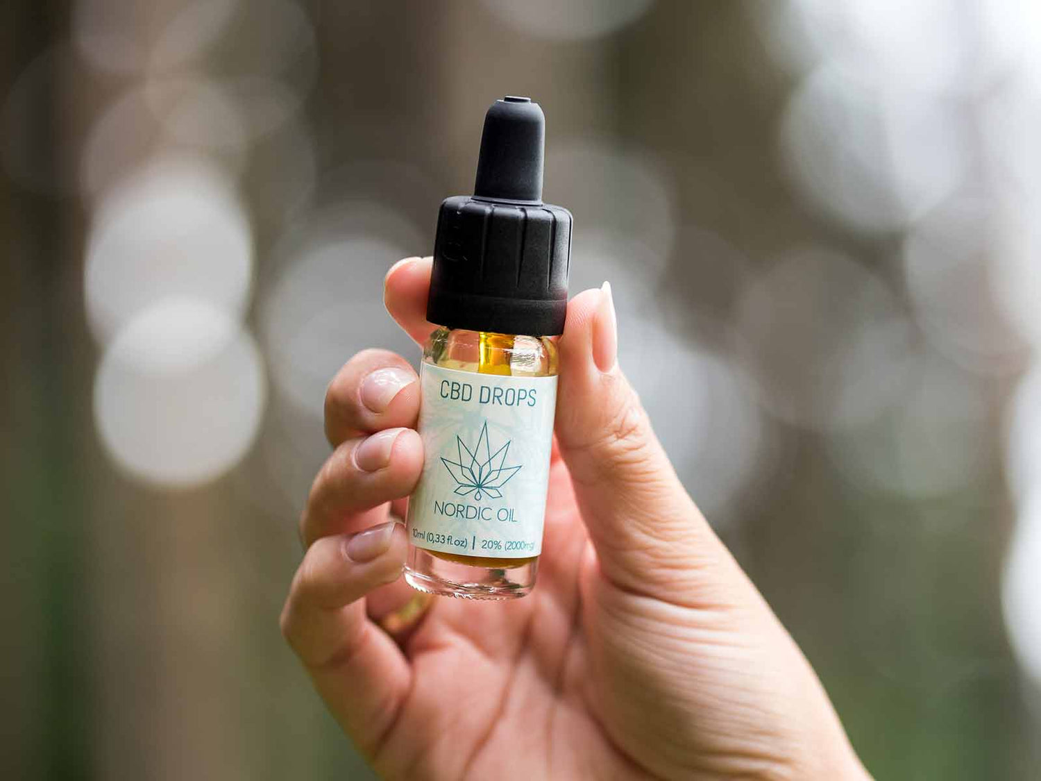 女性の手にはCBDオイルのボトルが握られています。