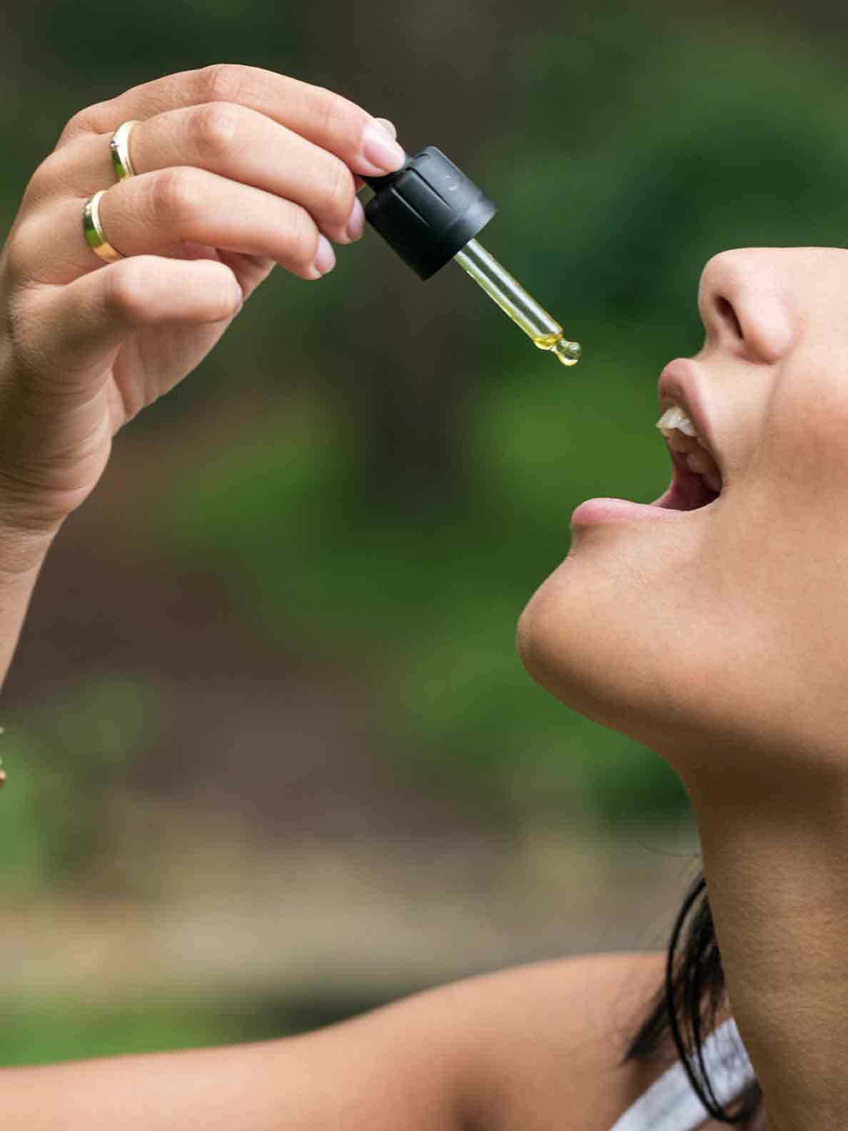 CBDオイルを口に垂らす女性。