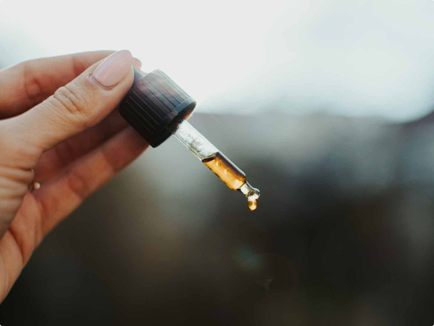 女性の手にはCBDオイルの入ったピペットが握られています。
